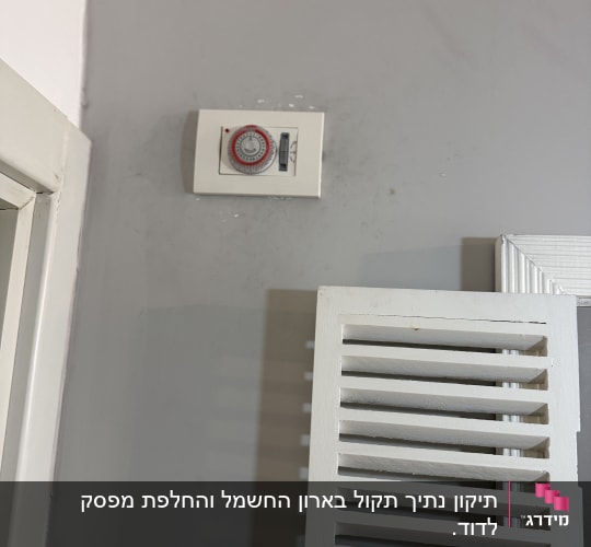 תרמוסטט על קיר אפור ליד תריס לבן